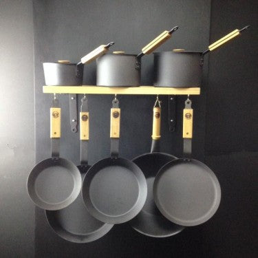 Ultimate spun iron pan set with oak wall rack, 99% iron pans arranged on hooks