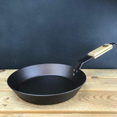 12-inch spun iron steak skillet with British oak handle on rustic table