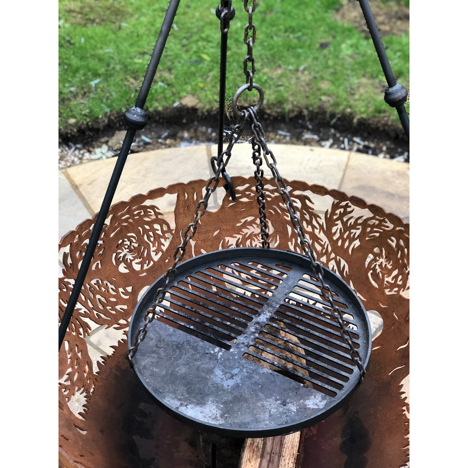 tripod cooking stand with view of cooking grate and wood in burner