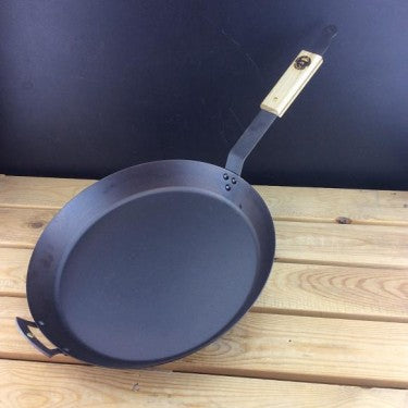 Spun black iron skillet on rustic wooden table