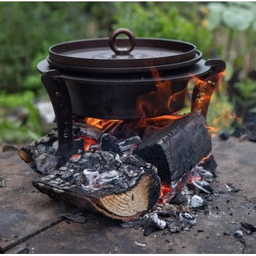 Netherton Foundry spun iron Dutch oven with hot coals lid and stand assembled outdoors