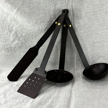 Black iron cooking utensil set on rustic wooden surface