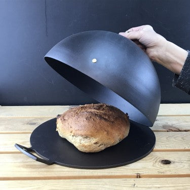 spun iron baking bell dome over loaf on griddle plate