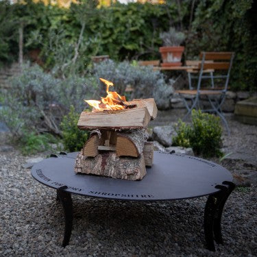 Spun black iron fire table on steel stand outdoors