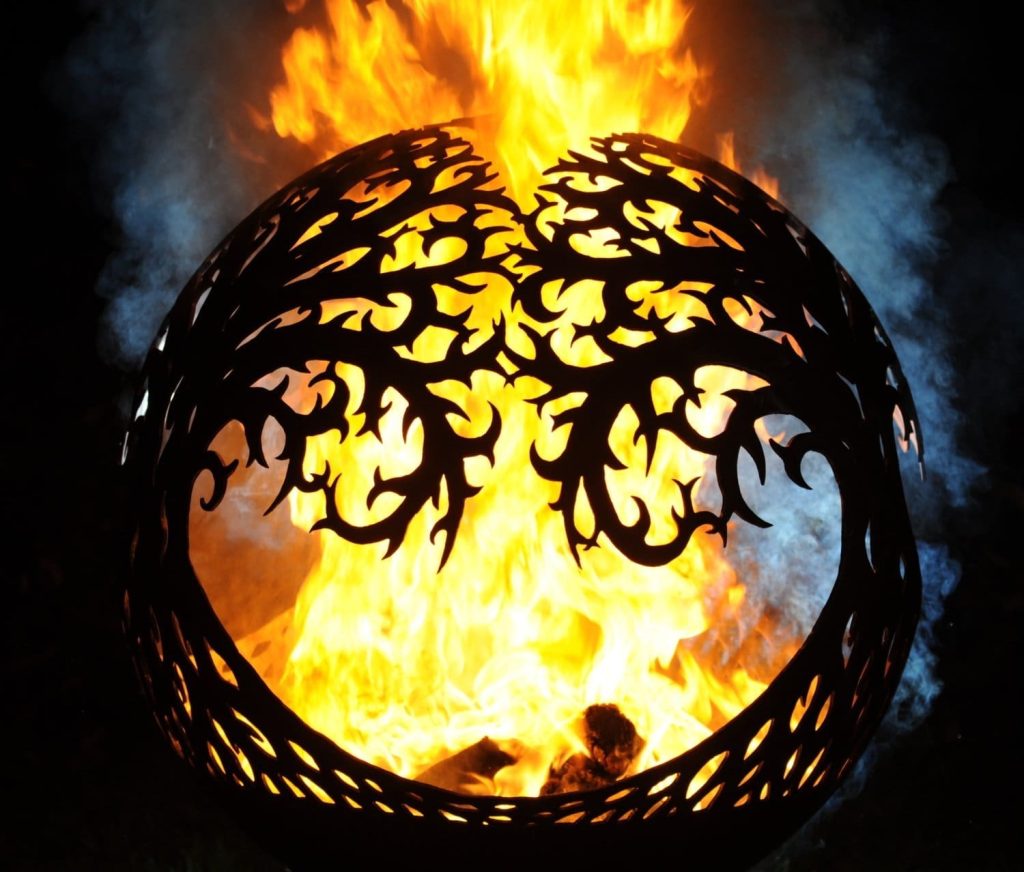 tree of life fire container with large flames at night