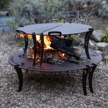 Giant split black iron griddle plates with removable legs over fire table