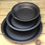 Three spun iron pie dishes stacked in rustic kitchen settin